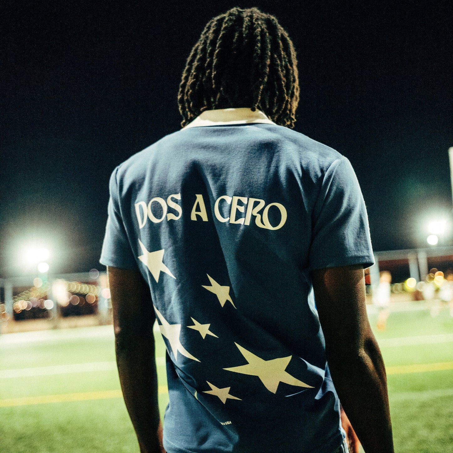 PAS x USA Dos A Cero blue slim fit polo – embroidered PAS x USA arch on front, Dos A Cero stars graphic on back, PAS patch on sleeve