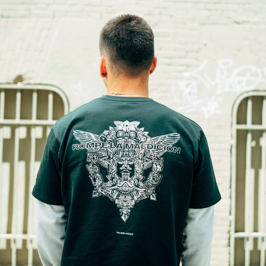 PAS x Mexico Rompe La Maldición El Tri dark green tee – Aztec back graphic with Rompe La Maldición text, worn against urban wall